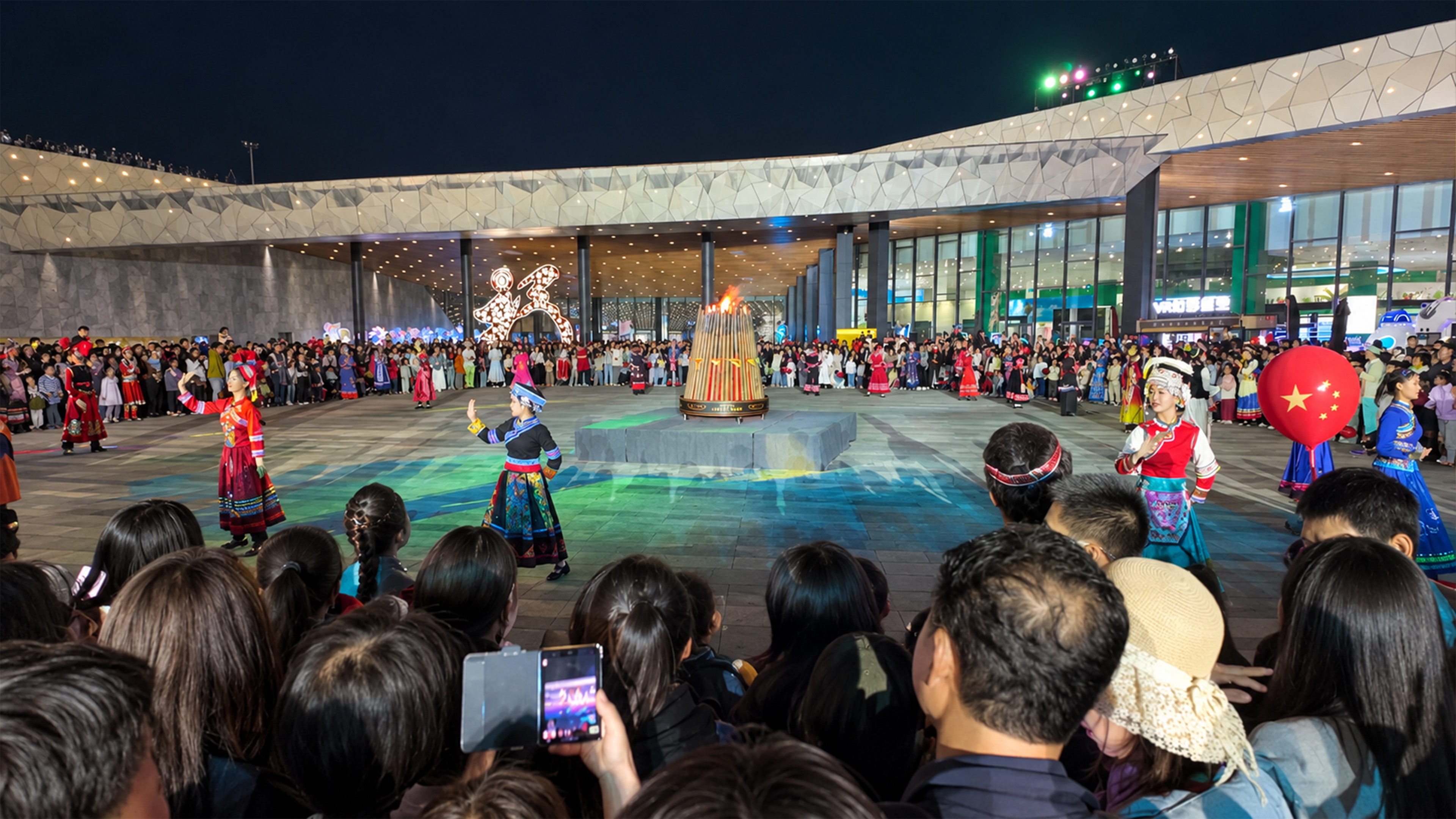 Traditional Chinese dancers perform outside a futuristic building at night
