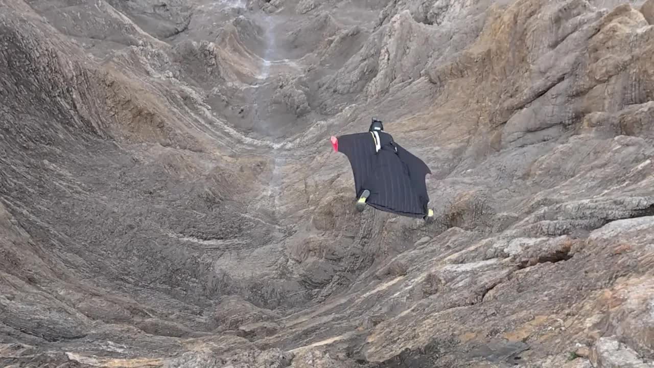 Wingsuit flying along a mountain ridge in the Swiss Alps