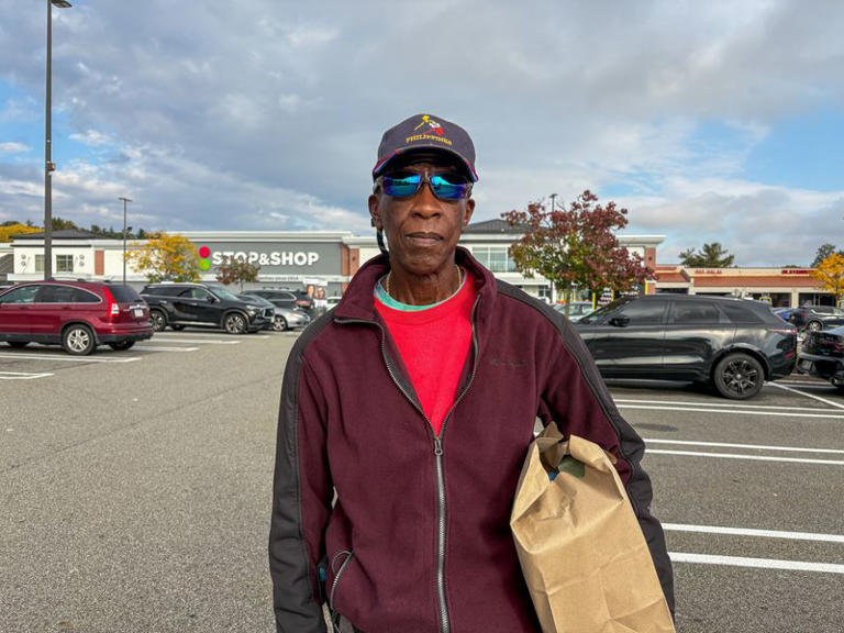 Tyrone Benjamin, 70, holds a paper grocery bag in front of a Stop and Shop store in Peekskill, New York, a politically divided area in the US, October 16, 2026. Picture taken with a mobile phone. REUTERS/Danielle Kaye
