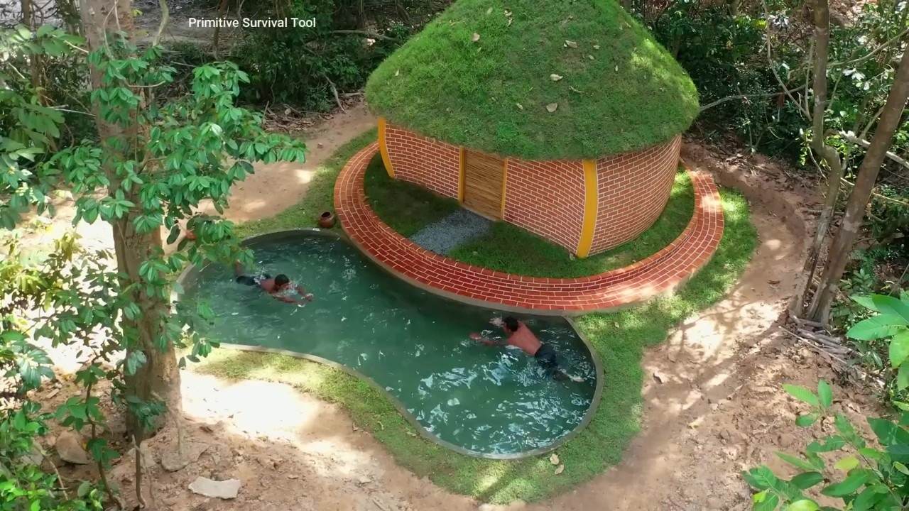Green-roofed hobbit house beside a curved pool