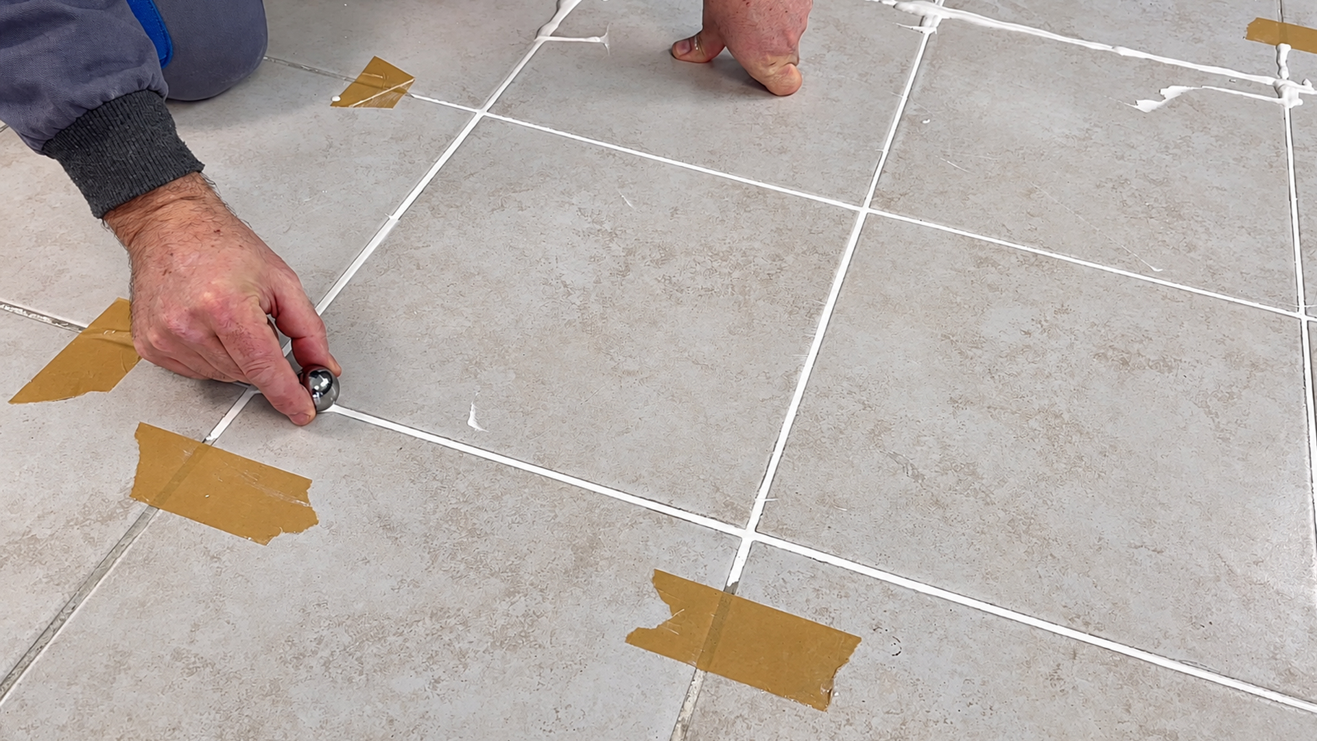 Watch a tiler cut out old grout with diamond discs and reseal tile seams