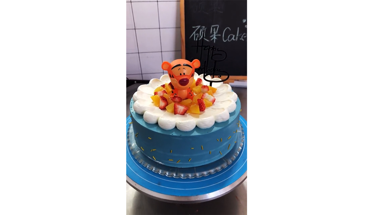 Decorating blue birthday cake with cute Tigger topper and fresh ...
