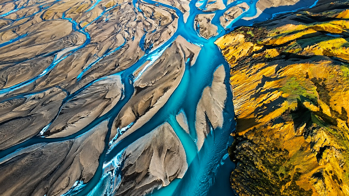Turquoise glacial rivers flow through vast sandbanks and golden ...