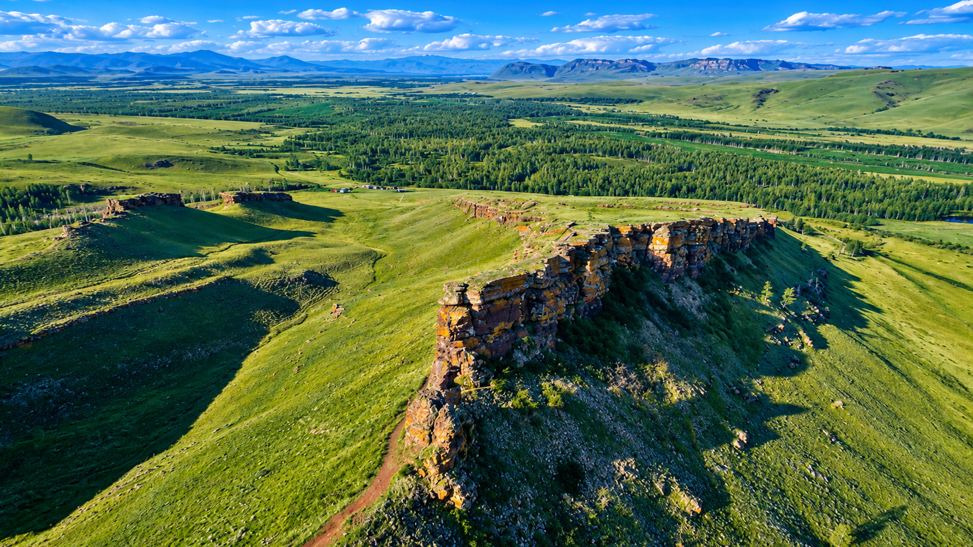Giant rock cliffs rise above Siberia's endless steppe