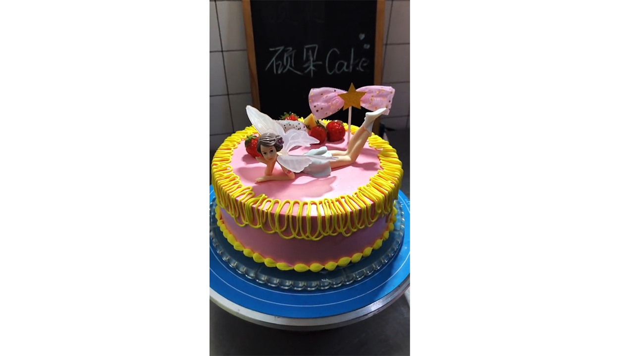 Decorating pink fairy birthday cake with golden buttercream borders