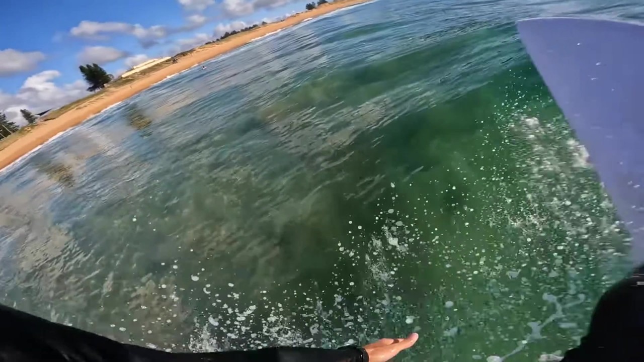 Surfer carves across a steep green wave in POV