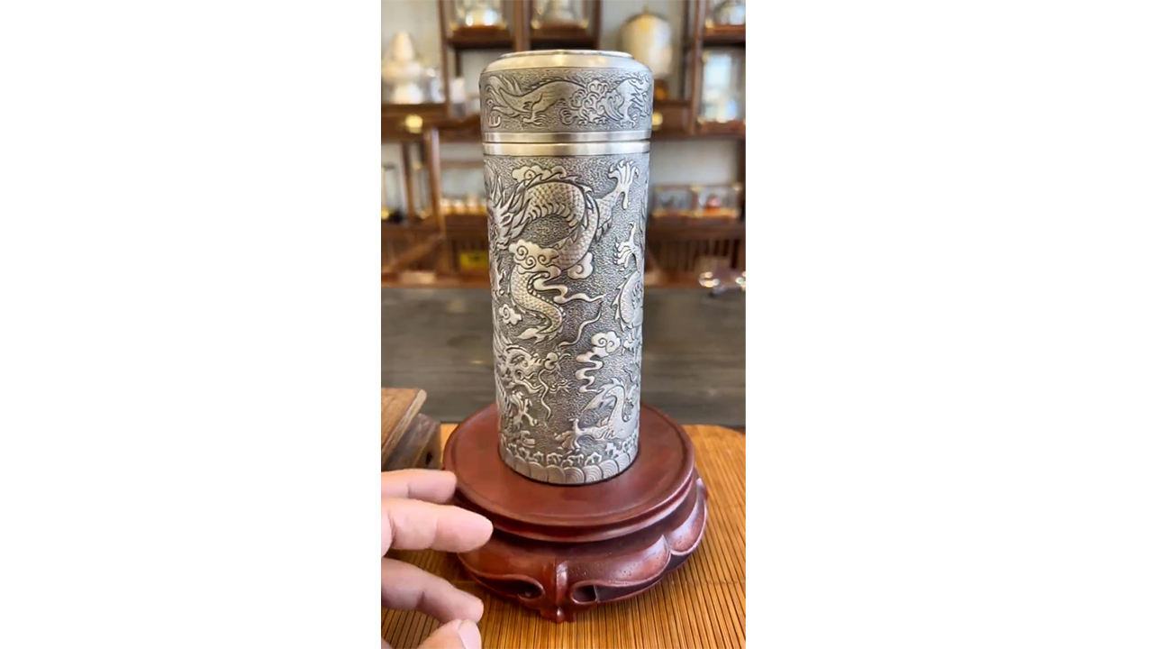 Crafting silver-colored metal into dragon-engraved tea canister ...