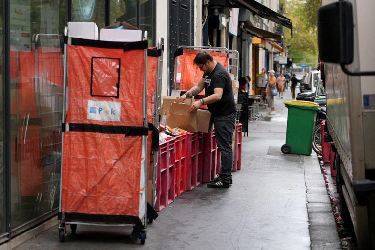 An employee fills boxes of perished goods outside an Intermarche supermarket in Paris the day after a cyberattack targeted refrigeration systems at French supermarket chains, causing food losses and fires at several stores, France, October 13, 2026. REUTERS/Lucien Libert