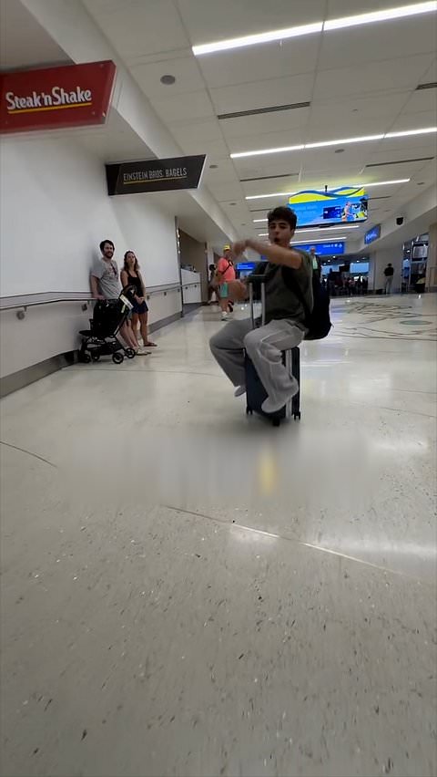 Man takes a tumble while riding suitcase through airport