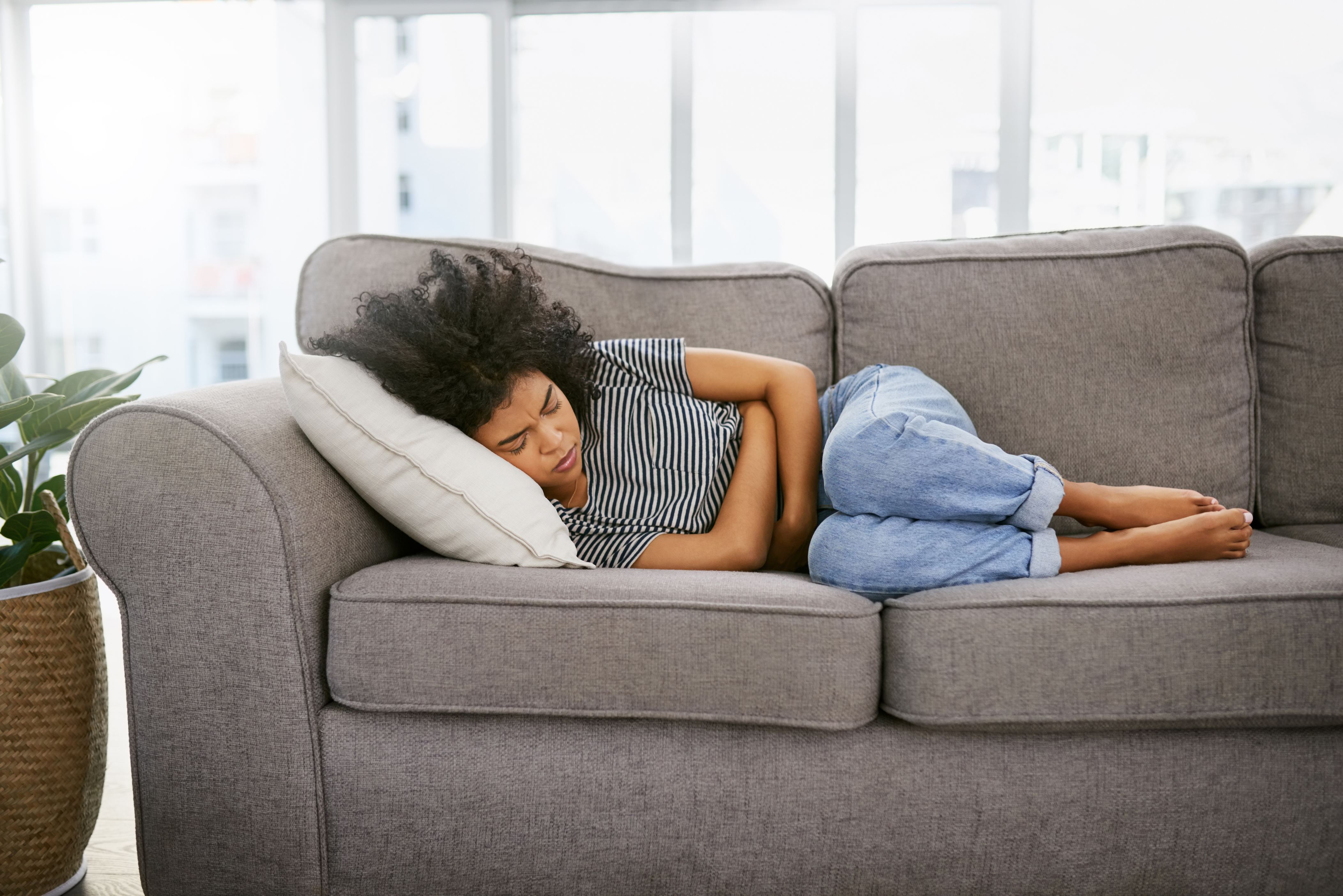 Shot of a young woman experiencing stomach pain on the sofa at home