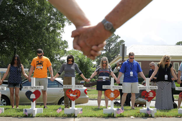 Slide 3 of 31: VIRGINIA BEACH, VIRGINIA - JUNE 02:  People hold hands and pray together at a makeshift memorial for the 12 victims of a mass shooting at the Municipal Center June 02, 2019 in Virginia Beach, Virginia. Eleven city employees and one private contractor were shot to death Friday in the city's operations building by engineer DeWayne Craddock who had worked for the city for 15 years. (Photo by Chip Somodevilla/Getty Images)