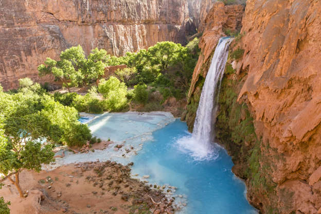 Слайд 15 из 16: Havasu Falls plunges into a deep blue-green pool, with Cataract Canyon behind lit by the morning sun, on Havasupai Indian Reservation in the Grand Canyon.
