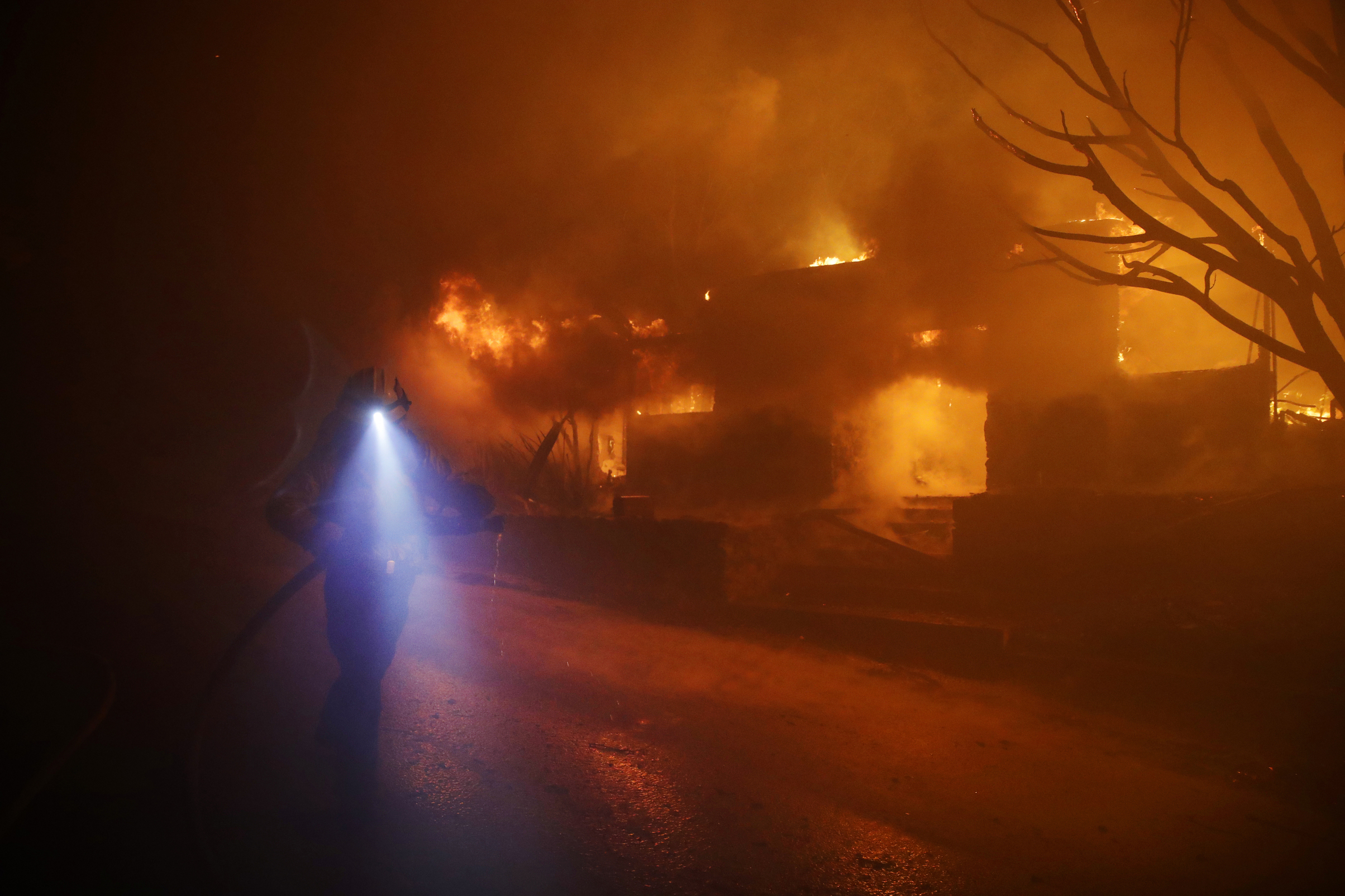 Slide 4 of 44: A firefighters gets in position to hose down flames as a home burns in the Getty fire area along Tigertail Road, Monday, Oct. 28, 2019, in Los Angeles.