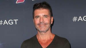 Simon Cowell holding a sign posing for the camera