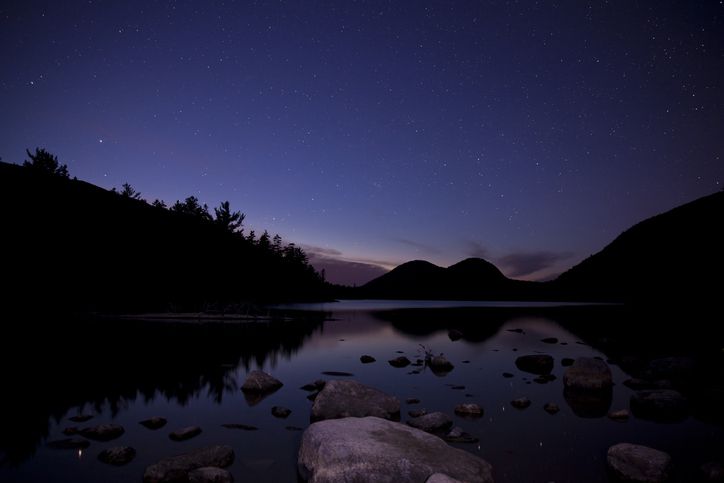 <p>The open skies above Jordan Pond offer another clear view of the night sky framed by mountains.</p>