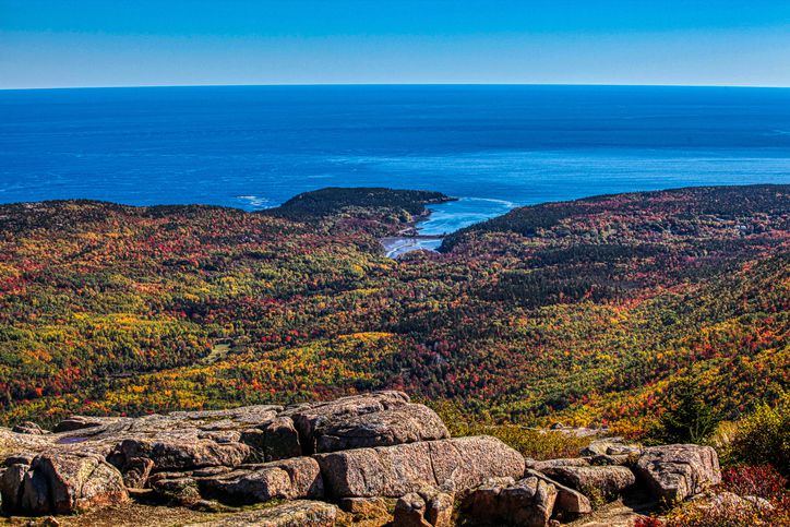 Slide 18 of 29: Some of the best places to view the fall foliage in Acadia National Park are from higher points that overlook it. This photo, taken from the top of Cadillac Mountain, shows the  leaves in all their splendor.