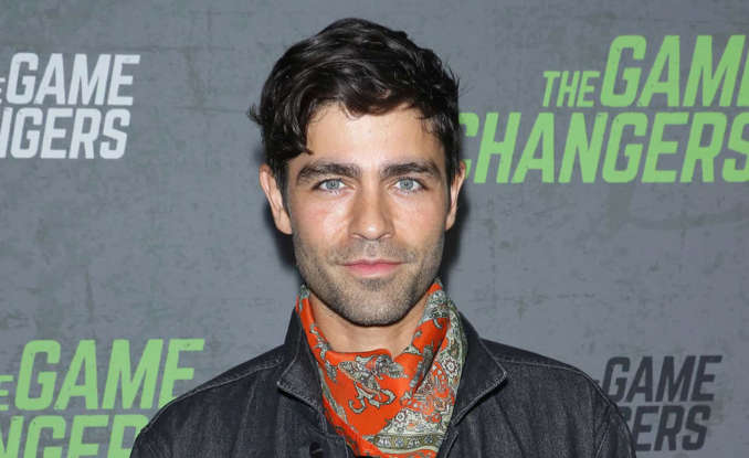Adrian Grenier standing in front of a building