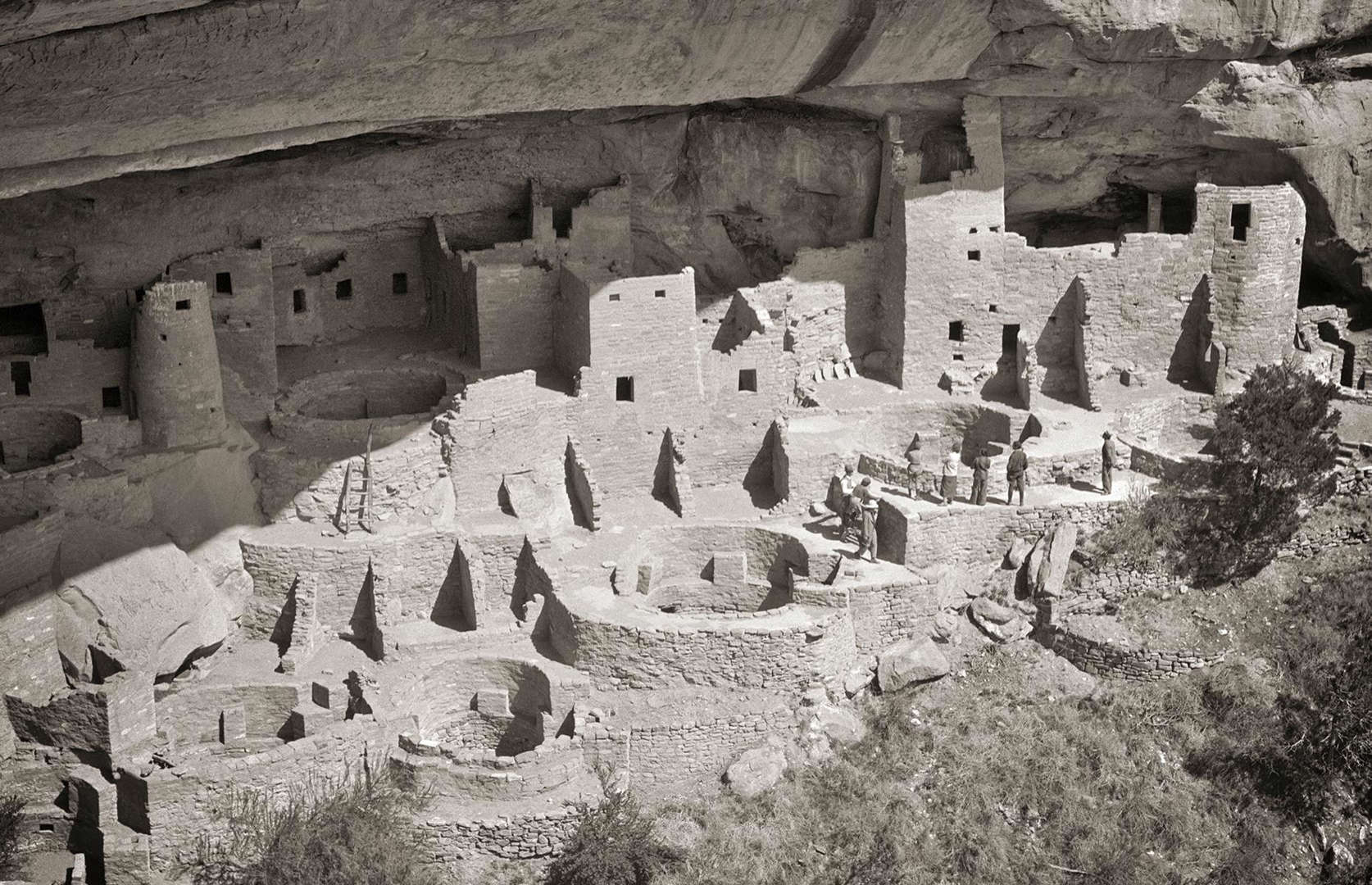 Slide 36 of 41: America's ancient landmarks are often forgotten, but sites across the States offer intriguing insights into the country's earliest settlers. Among them is Mesa Verde National Park and its Cliff Palace, an incredible 150-room dwelling built up by Ancestral Pueblo people from around AD 1190 to 1260. It's pictured here in the 1930s, and you can see tourists wandering about the walls and kivas.