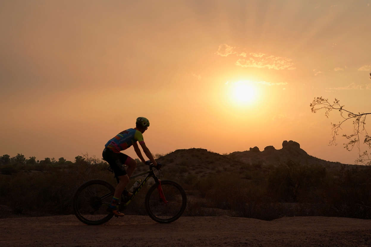 Slide 21 of 27: A cyclist bikes past the setting sun at Papago Park during a heatwave where temperatures hit 115-degrees Tuesday, June 15, 2021, in Phoenix.