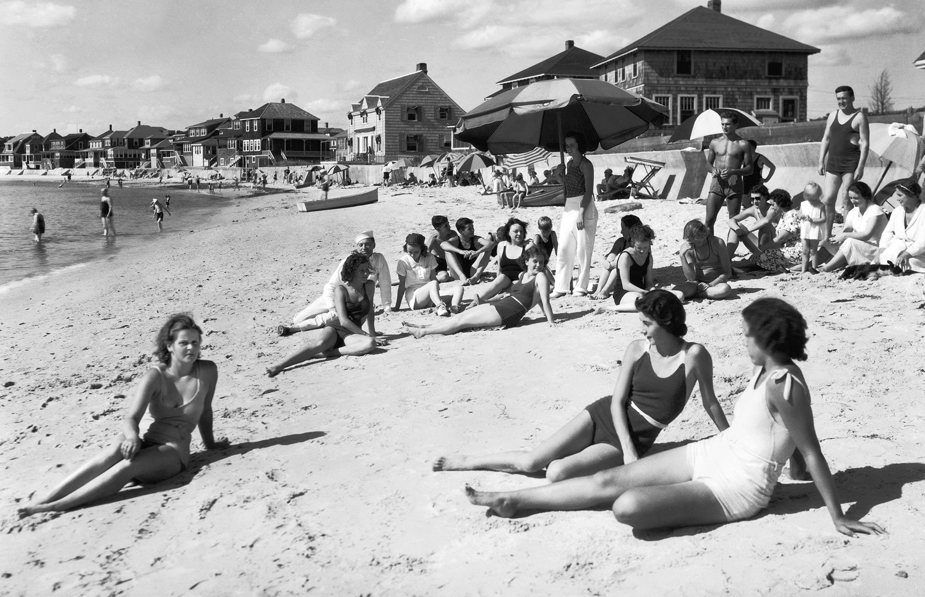Arguably Massachusetts' most famous destination, Cape Cod has been drawing in vacationers for more than a century. This photograph, taken at the tail end of the Roaring Twenties, pictures glamorous young sunbathers basking on a beach at Buzzards Bay. The neat waterside houses and patterned umbrellas no doubt brighten the scene.