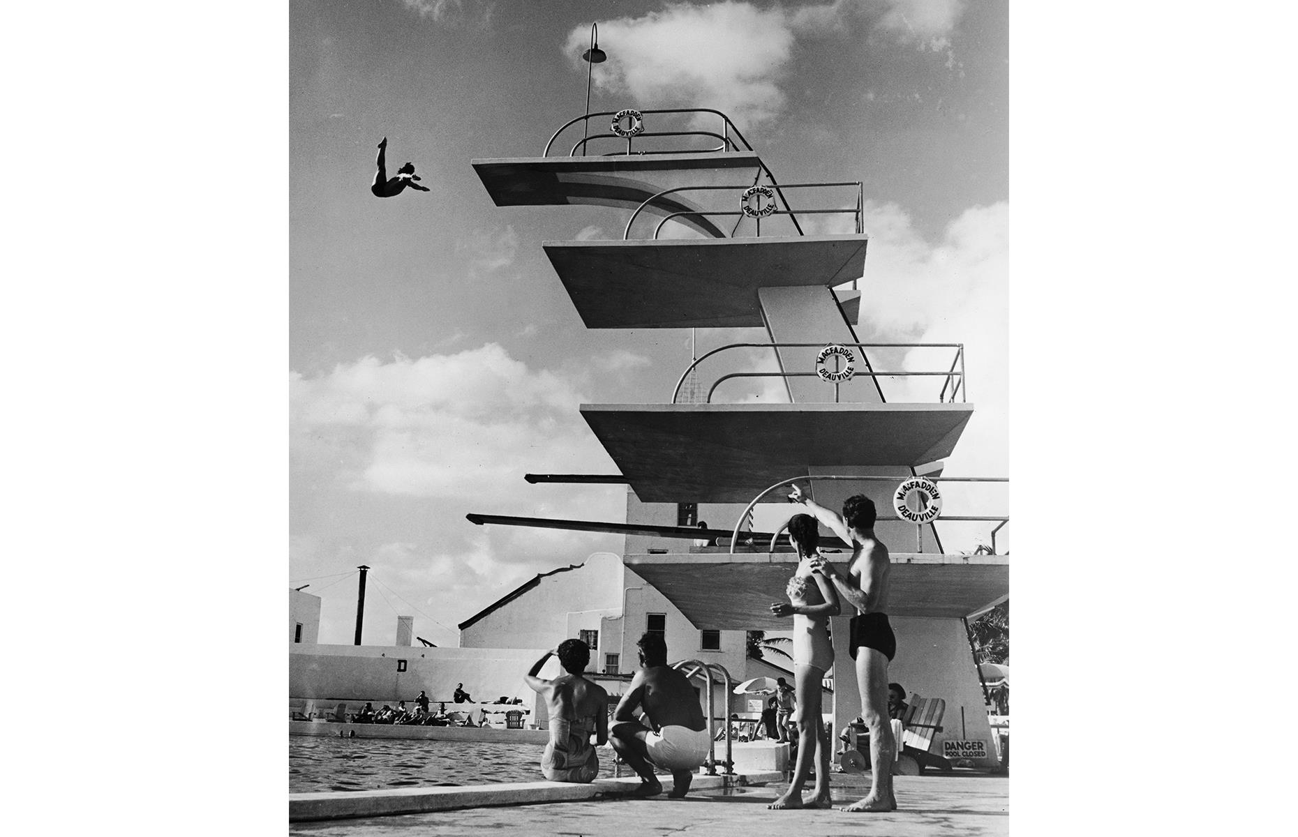 In fact, the 1950s and 1960s are often tipped as Miami Beach's golden era for tourism. Hotels, resorts and other attractions continued to shoot up and celebs, couples and families alike continued to spend their vacation time here. This 1950s photo is taken at Miami Beach's Deauville Beach Resort (then the MacFadden-Deauville Hotel) and sees vacationers gaze up in awe as a man jumps off the highest diving platform.