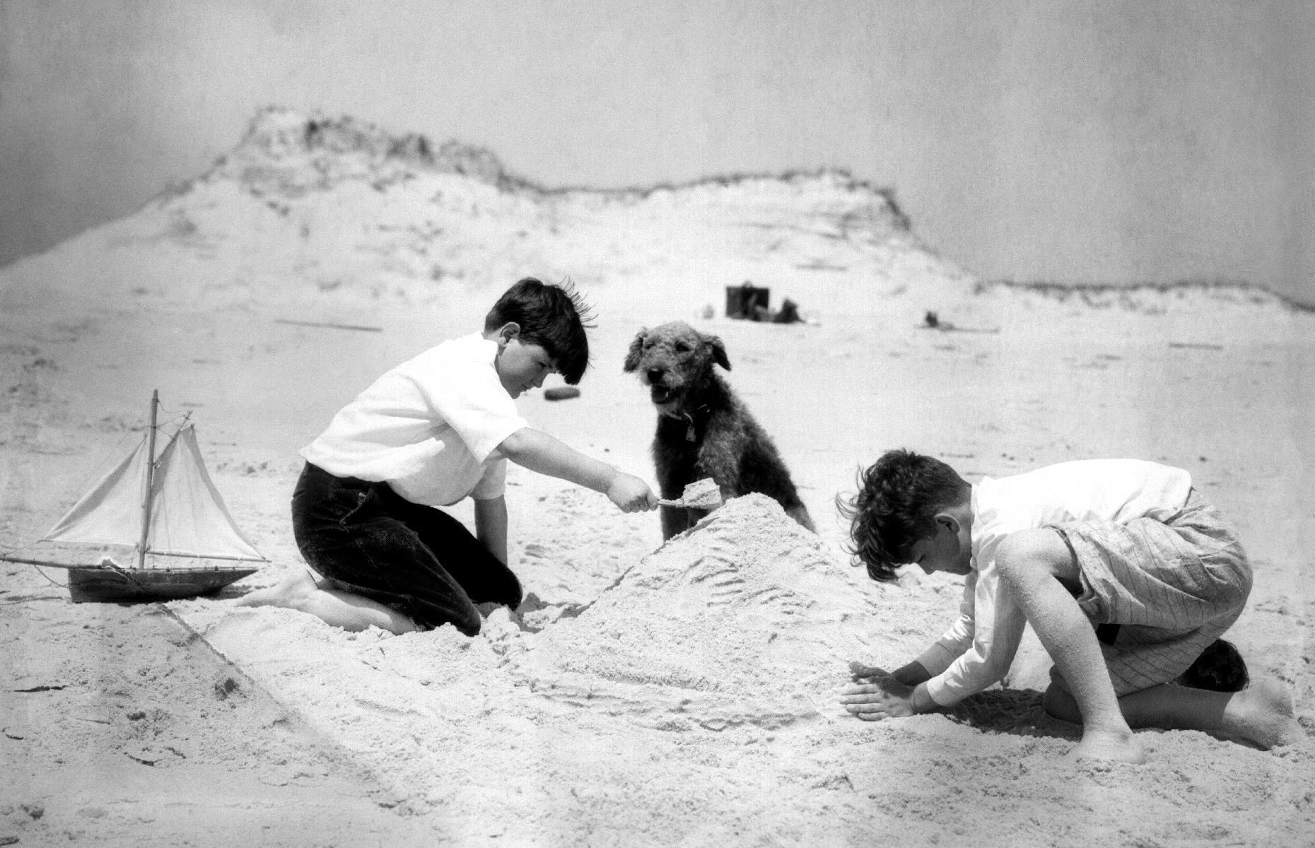 Four-legged folks enjoyed the coast as well. Here, on a quieter stretch of the New Jersey shore, two young beach-dwellers build a pawfect-looking sandcastle under the watchful eye of their canine companion. The heartwarming seaside scene was captured in 1934.