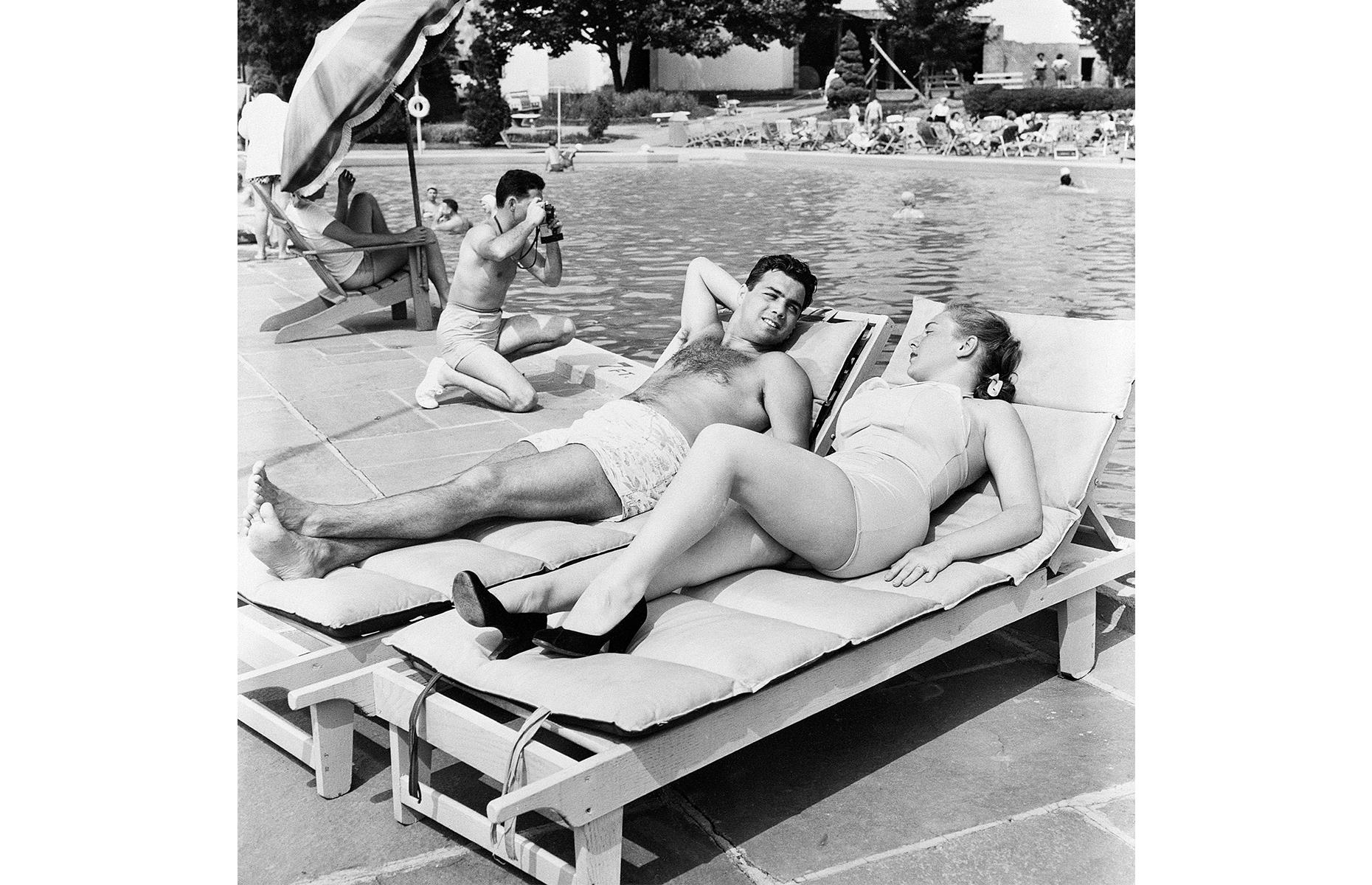 Farther up the state, the Catskill Mountains region proved popular with vacationers in the 1950s and beyond. Here a well-heeled couple relax by the pool in a swish resort in New York's Sullivan County in 1953. A man kneels to photograph his family in the pool beside them.