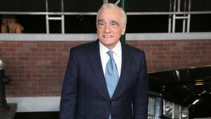 Martin Scorsese wearing a suit and tie standing in front of a building: The legendary director grew up in a very devout Sicilian family and entered a preparatory seminary aged 14 to become a priest.  Like Tom Cruise, Scorsese didn’t end up continuing his education at the school of theology, as his lack of discipline in class thwarted those plans and told ‘Good Morning America’: “I was invited to leave at the end of that year.” Cinema welcomed him with open arms, and the rest is history!