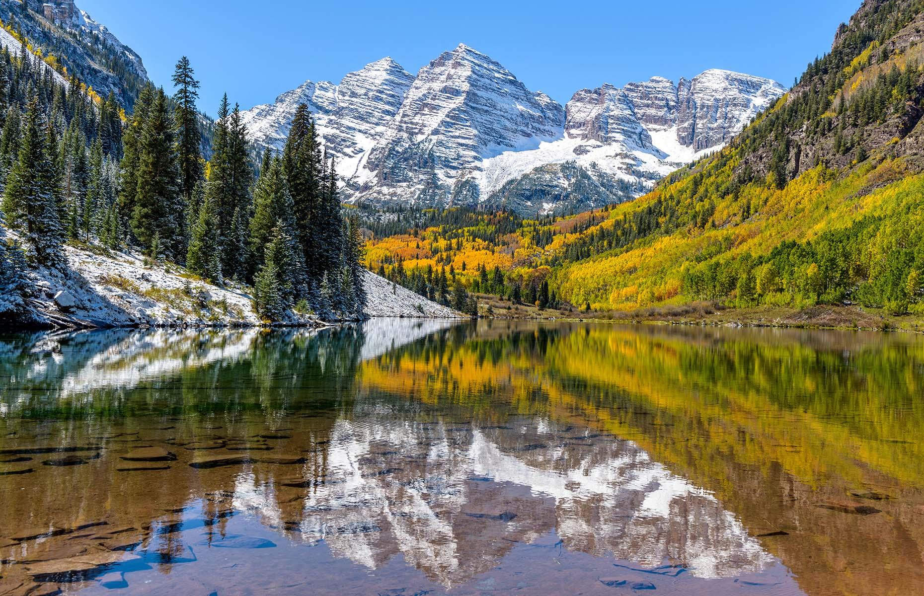 The Elk Mountains in Colorado are crammed full with inspiring viewpoints and enchanting landscapes. Yet of all of them, nowhere is quite like the Maroon Bells. Two of the highest peaks in the region, these soaring mountains reflect in Crater Lake during sunny days, creating a natural mirror that captures this untouched landscape.