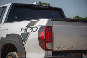 a truck is parked in front of a car: 2021 Honda Ridgeline Sport HPD