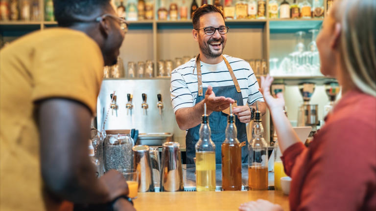 happy bartender jokes with customers successful small business concept_iStock-1347121532