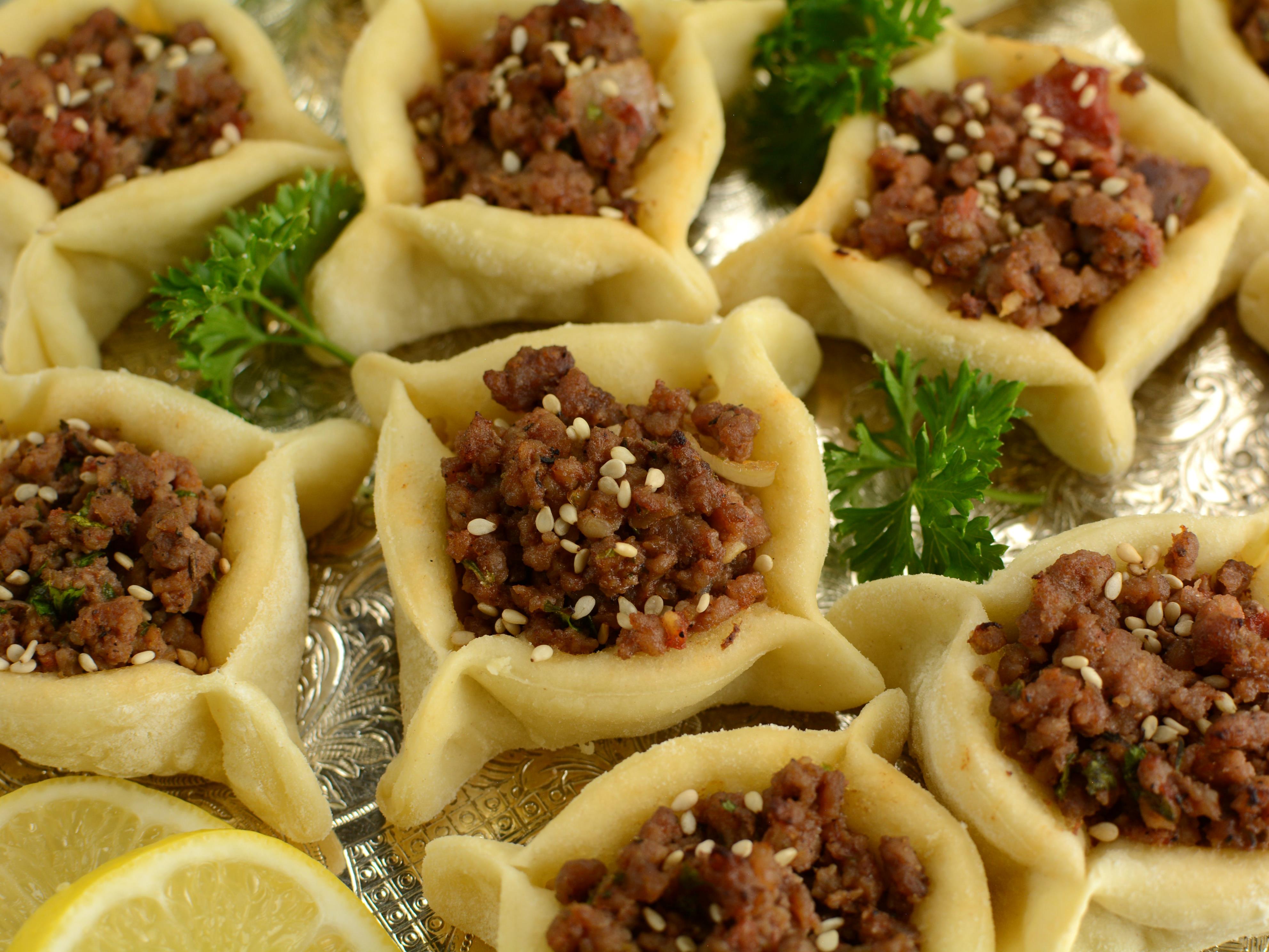 <p><a href="https://thelemonbowl.com/lebanese-meat-pies-sfeehas/">These</a> savory meat pies are made with butter, pine nuts, and cinnamon. </p><p>The filling is made of <a href="https://www.insider.com/best-ground-beef-recipes-2018-12">ground beef</a> or lamb sauteed in butter and allspice.</p><p>They're commonly eaten with stuffed grape leaves, hummus, or plain yogurt. </p>