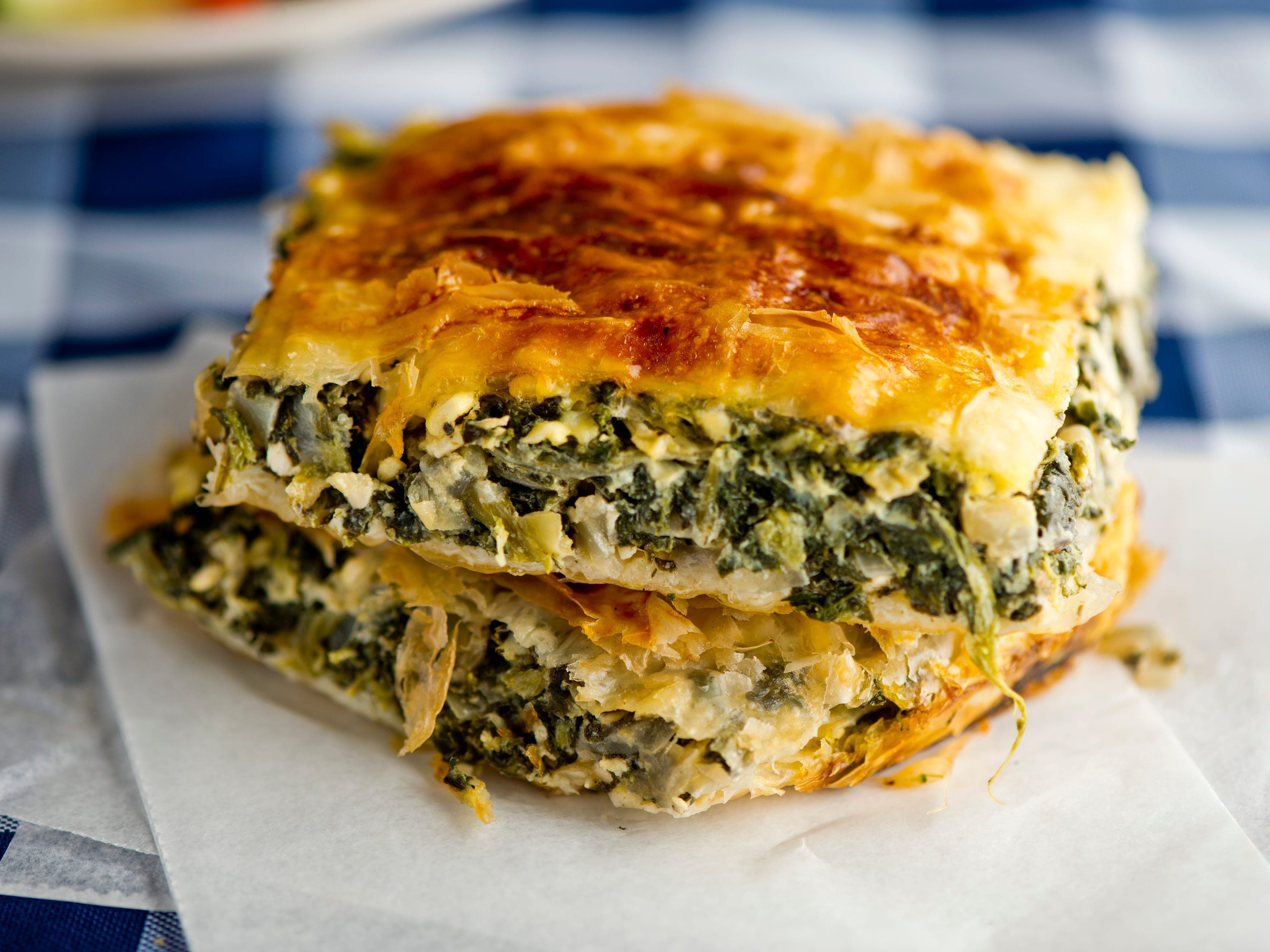 <p><a href="https://www.allrecipes.com/recipe/18417/spanakopita-greek-spinach-pie/">According to All Recipes</a>, spanakopita is a flaky pie packed with cooked spinach, onions, feta cheese, eggs, and seasoning.</p><p>The handheld treat usually features a top and base made of phyllo — a delicate and incredibly thin pastry.</p>