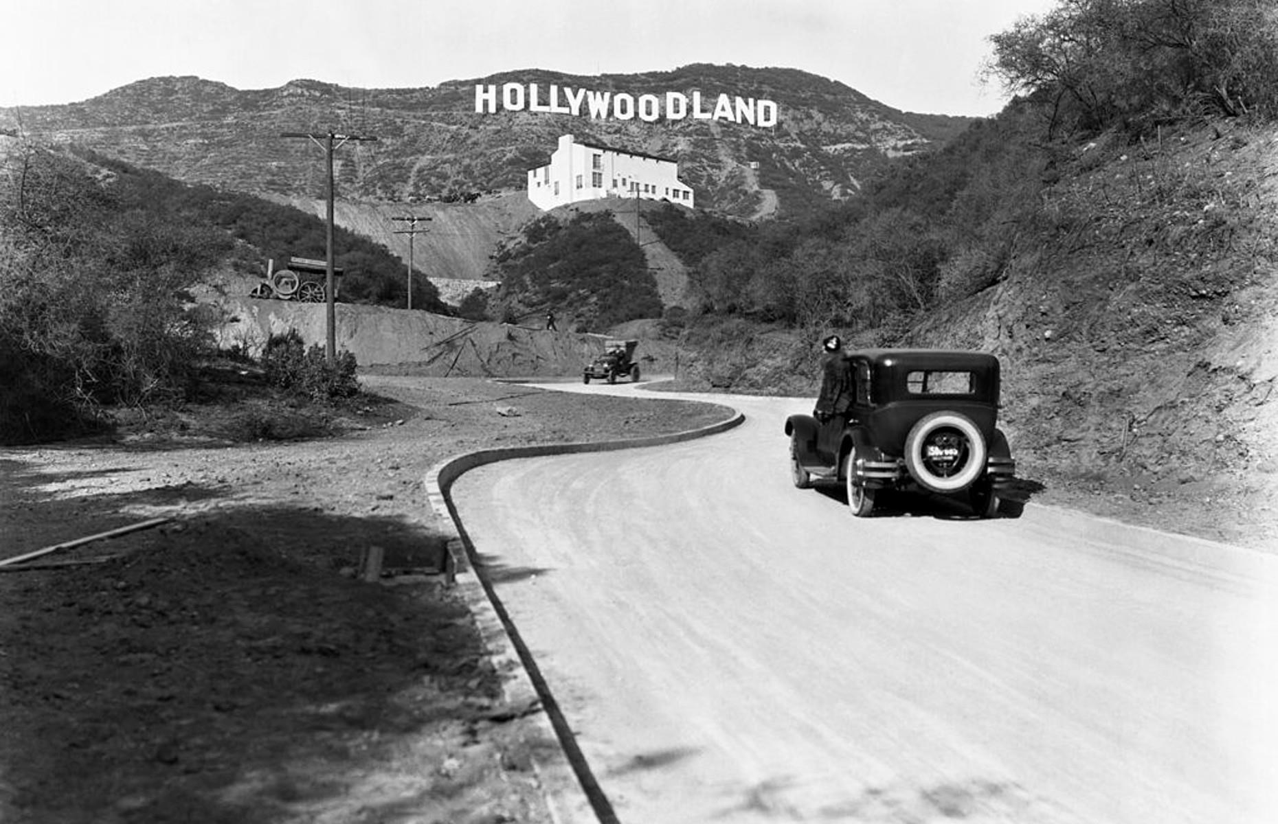 <p>Here, a sign advertises the opening of the Hollywoodland housing development in the Mulholland Drive hills in 1924. The white building is the Kanst Art Gallery. The large film companies, such as Warner Bros. and Colombia, had already arrived and they brought the movie stars, the development and, of course, the tourists who now dominate this area.</p>  <p><a href="https://www.loveexploring.com/guides/88050/where-to-go-in-los-angeles-hollywood-beverly-hills-silver-lake-venice-beach"><strong>Delve into Los Angeles' neighborhoods with our guide</strong></a></p>