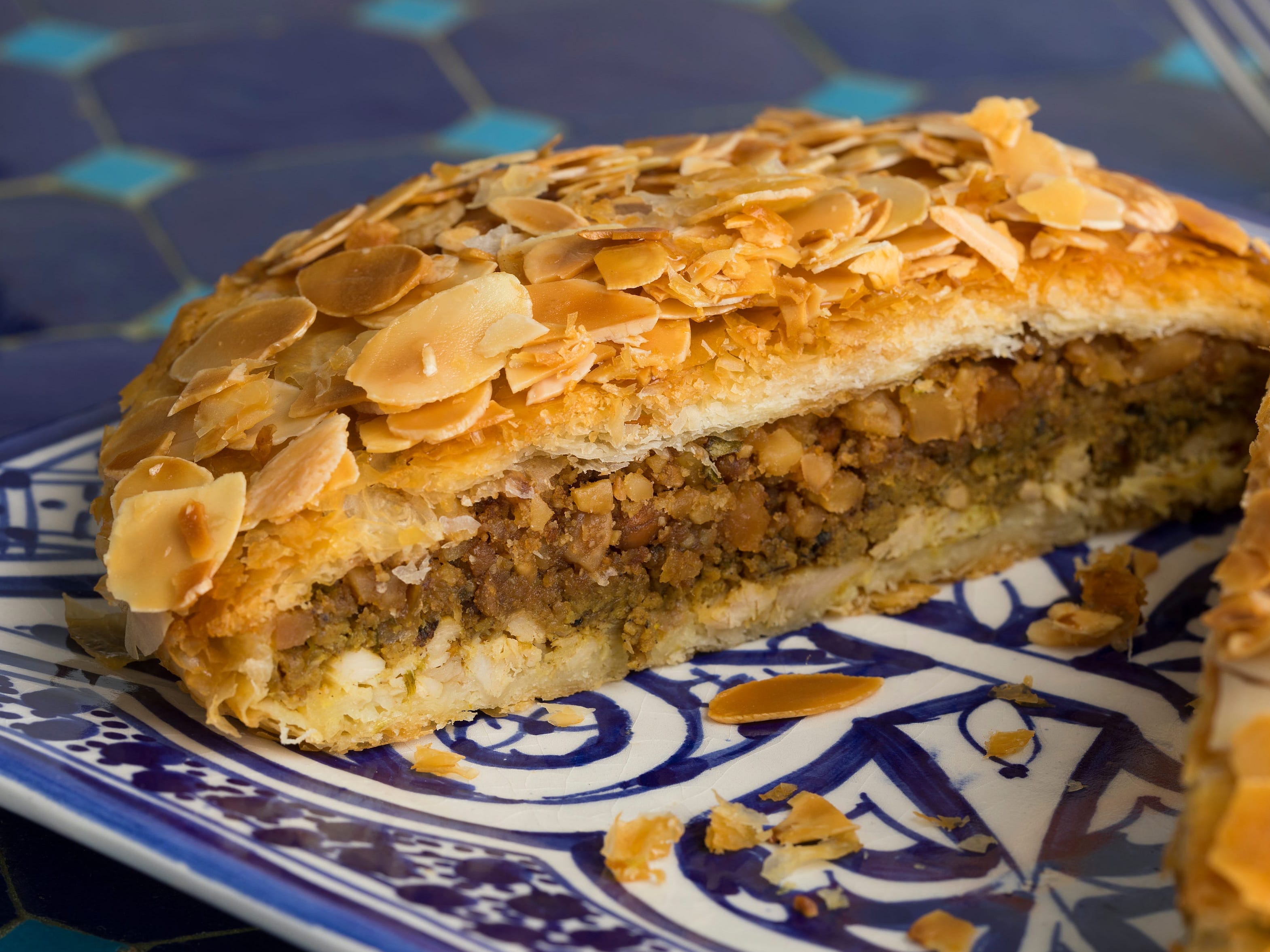 <p><a href="https://www.taste.com.au/recipes/bisteeya-moroccan-chicken-almond-filo-pie/b56bd79a-09e8-46c6-97ac-50351a4d96eb">According to Taste</a>, this crumbly phyllo-coated Morrocan dish is commonly made with spicy chicken, almonds, and eggs.</p><p>After the chicken pie is baked, it's brushed with butter and sprinkled <a href="https://www.insider.com/sugar-cut-back-diet-health-experts-2019-9">with sugar</a> and cinnamon. </p>
