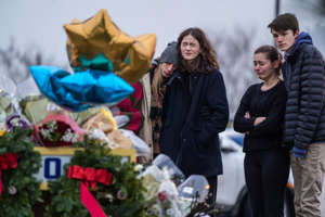 People get emotional at a memorial at an entrance to Oxford High School on Dec. 1, 2021, after a shooting attack left four students dead in Michigan.