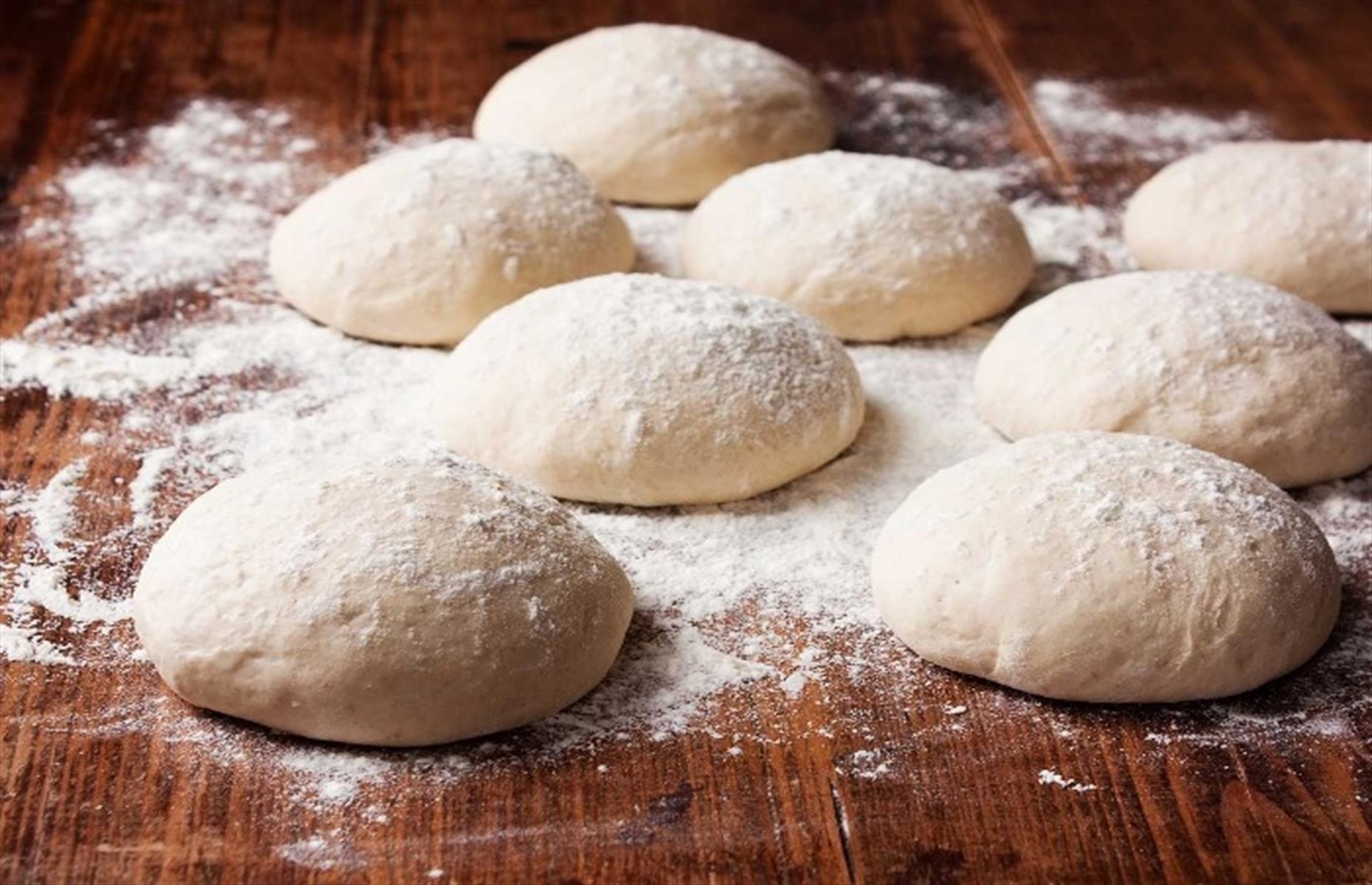 Once the dough is ready to shape into pizzas, it will be stretchy and pliable, so you can pull it into shape with your hands. Otherwise, use a rolling pin to start with. It should be uniform in thickness all over, and it's easy to coax it into being even by simply pulling the dough.