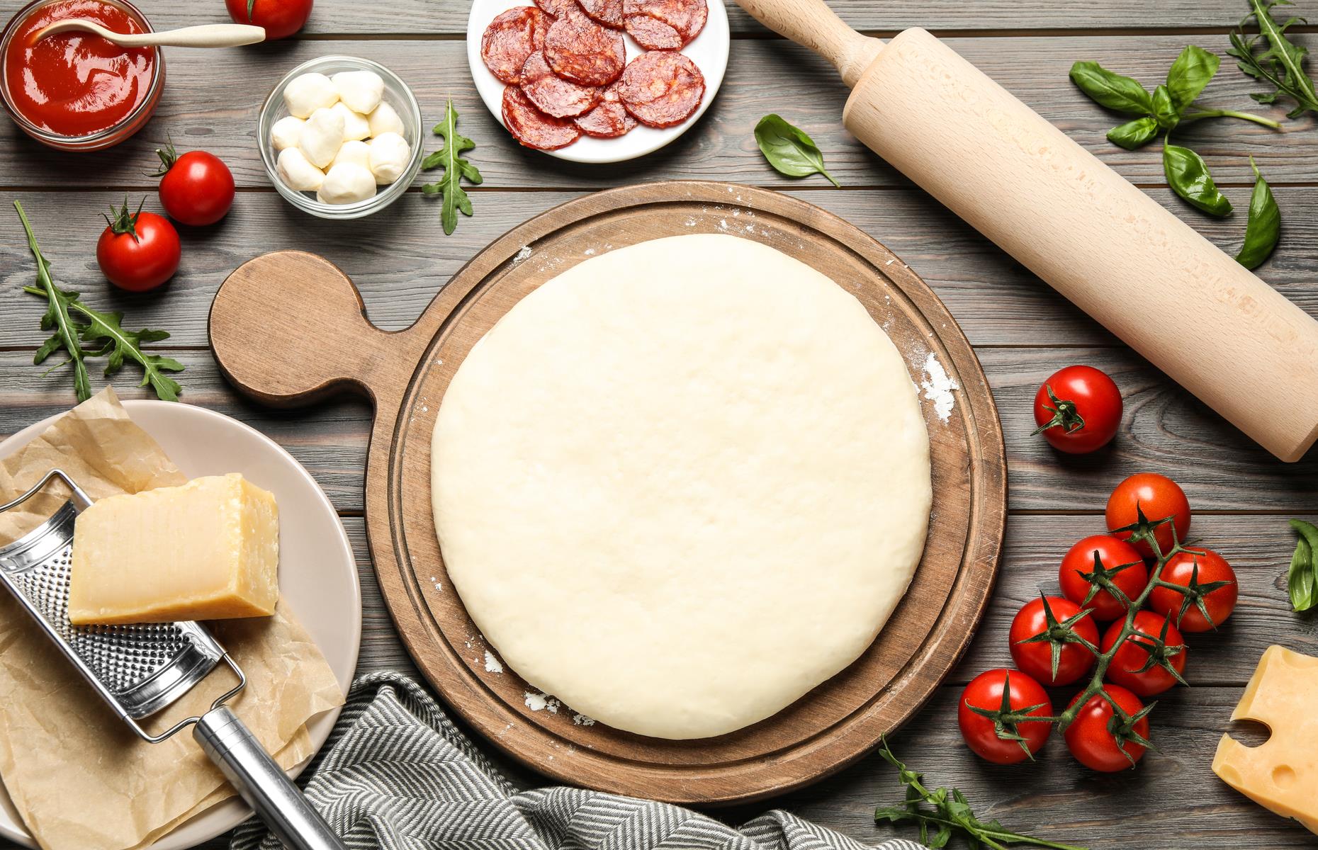 The question is – how do you get the assembled pizza on to a hot baking stone or metal pizza dish? Use a pizza paddle or a rimless baking sheet, well dusted with semolina or flour. Then it simply slides off into the oven without sticking.