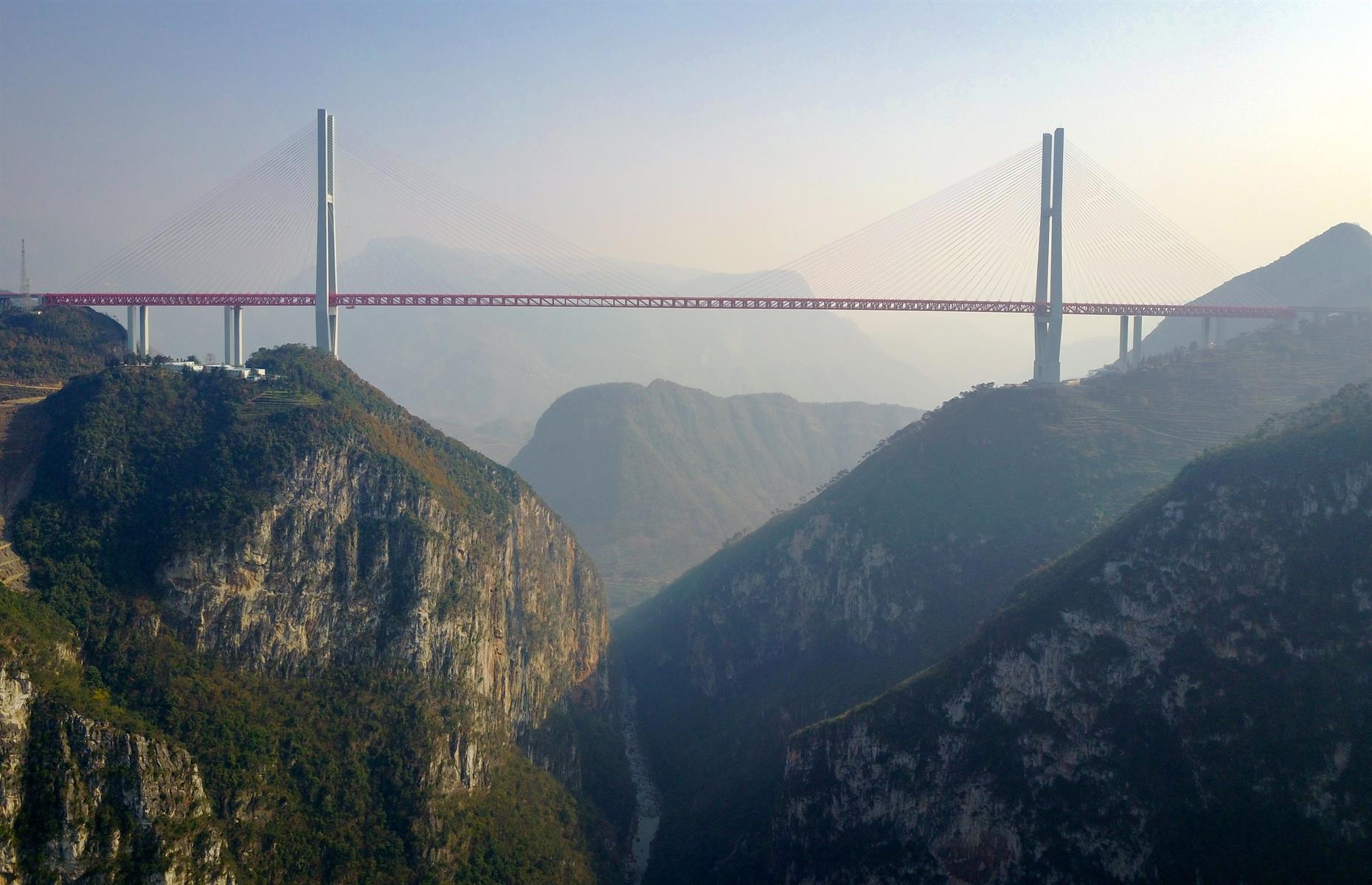 <p>Constructed between Xuanwei in Yunnan province and Liupanshui in Guizhou province in 2016, this mighty mountain overpass soars over the Beipan river in a remote and rugged part of southwestern China. Sitting at 1,854 feet (565m) above ground, the impressive cableway structure is the world's highest bridge. It is also pretty long at 2,363 feet (720m).</p>  <p><strong><a href="https://www.loveexploring.com/galleries/104228/breathtaking-bridges-you-can-walk-across">Discover the beautiful bridges you can walk across</a></strong></p>