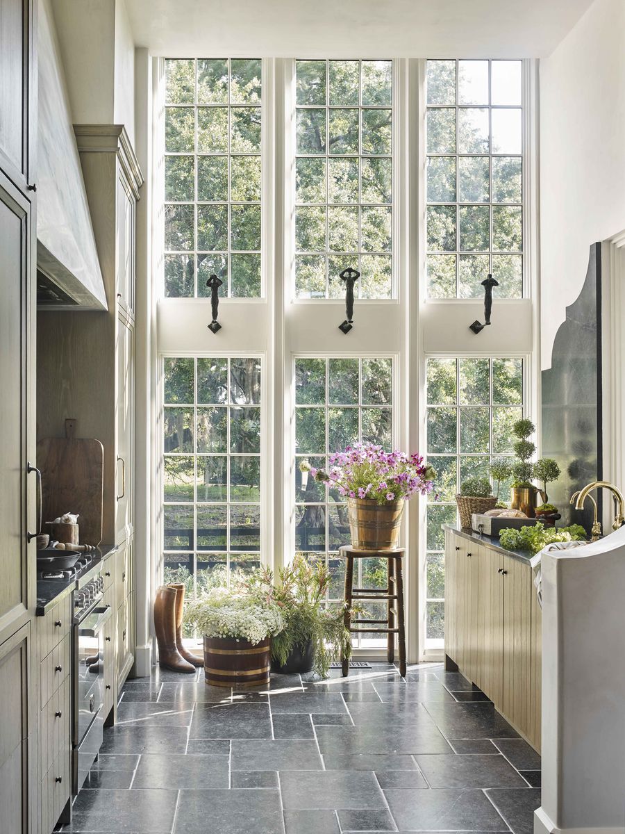 <p><a href="https://www.peterblockarchitects.com/">Architect Peter Block</a> designed the intimate kitchen galley in <a href="https://www.veranda.com/decorating-ideas/house-tours/a33487574/beth-webb-brays-island-house-tour/">Brays Island cottage</a> with windows that appear to soar higher than the ceiling. The striking wall sculptures pull the eye up and help prevent the kitchen from feeling “boxed in." The <a href="https://www.waterworks.com/">Waterworks</a> sink fixtures are in unlacquered brass. </p>