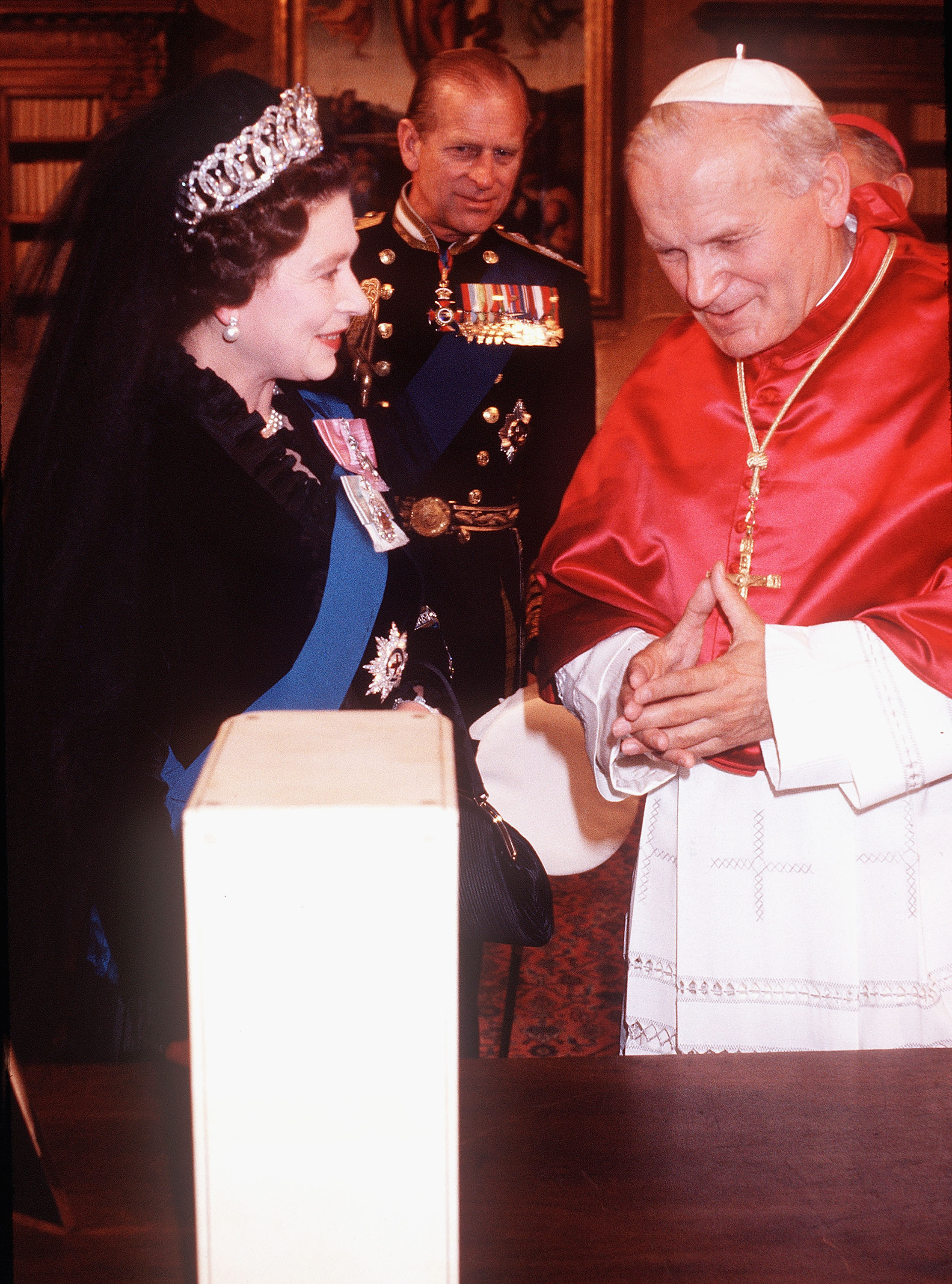 <p>Queen Elizabeth II wore a veil and a diamond tiara as she and husband Prince Philip met and exchanged gifts with Pope John Paul II in the Vatican on Oct. 17, 1980. She made history that day as she became the first British monarch to make a state visit to the Vatican -- the home of the Catholic Church.</p>