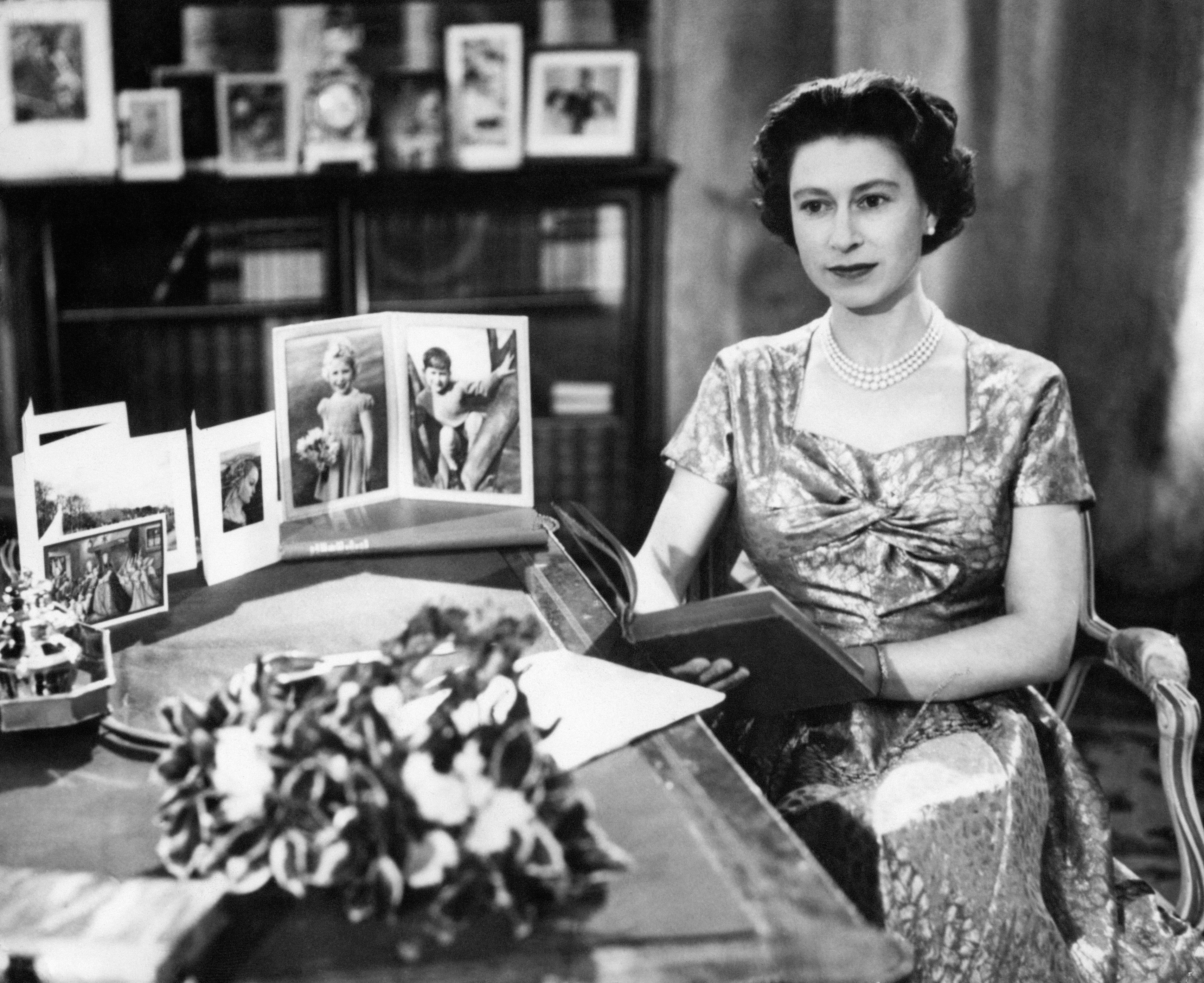 <p>Queen Elizabeth II, wearing a gold lamé dress, was photographed in the Long Library at her Sandringham estate on Christmas Day in 1957 shortly after making the traditional Christmas Day broadcast to the nation, which was televised that year for the first time ever. It was also the 25th anniversary of the first radio message to the Commonwealth made by her grandfather, King George V. On her desk were portraits of Prince Charles and Princess Anne. The queen held a copy of "Pilgrim's Progress," from which she read a few lines during her message. </p>