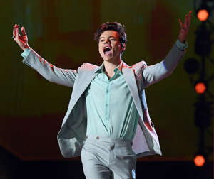 Harry Styles is a showstopper with an undeniable flair for fashion. The star,born Feb 1, 1994, first started as a contestant on ‘The X-Factor’ before catapulting to super-fame as part of One Direction. After the release of four studio albums, the band went on hiatus and Harry released his first solo debut album in 2017. Throughout his solo career, the hunky musician has made a habit of rocking over-the-top outfits on stage. From fashionable suits to patterned bell bottoms to brightly colored blouses, all of Harry’s ensembles have secured his status as a fashion icon. His style and swagger has gotten him often compared to the likes of Rolling Stones frontman Mick Jagger, which seems to only add to his charm. Here, Harry Styles beams while performing at the Victoria’s Secret fashion show. He wore a gray and seafoam Givenchy suit and showed off a shorter hairstyle.  Keep clicking through the gallery to check out Harry’s best style moments over the years!