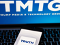 Truth Social (DWAC) app logo seen on the smartphone and blurred TMTG logo on the laptop.