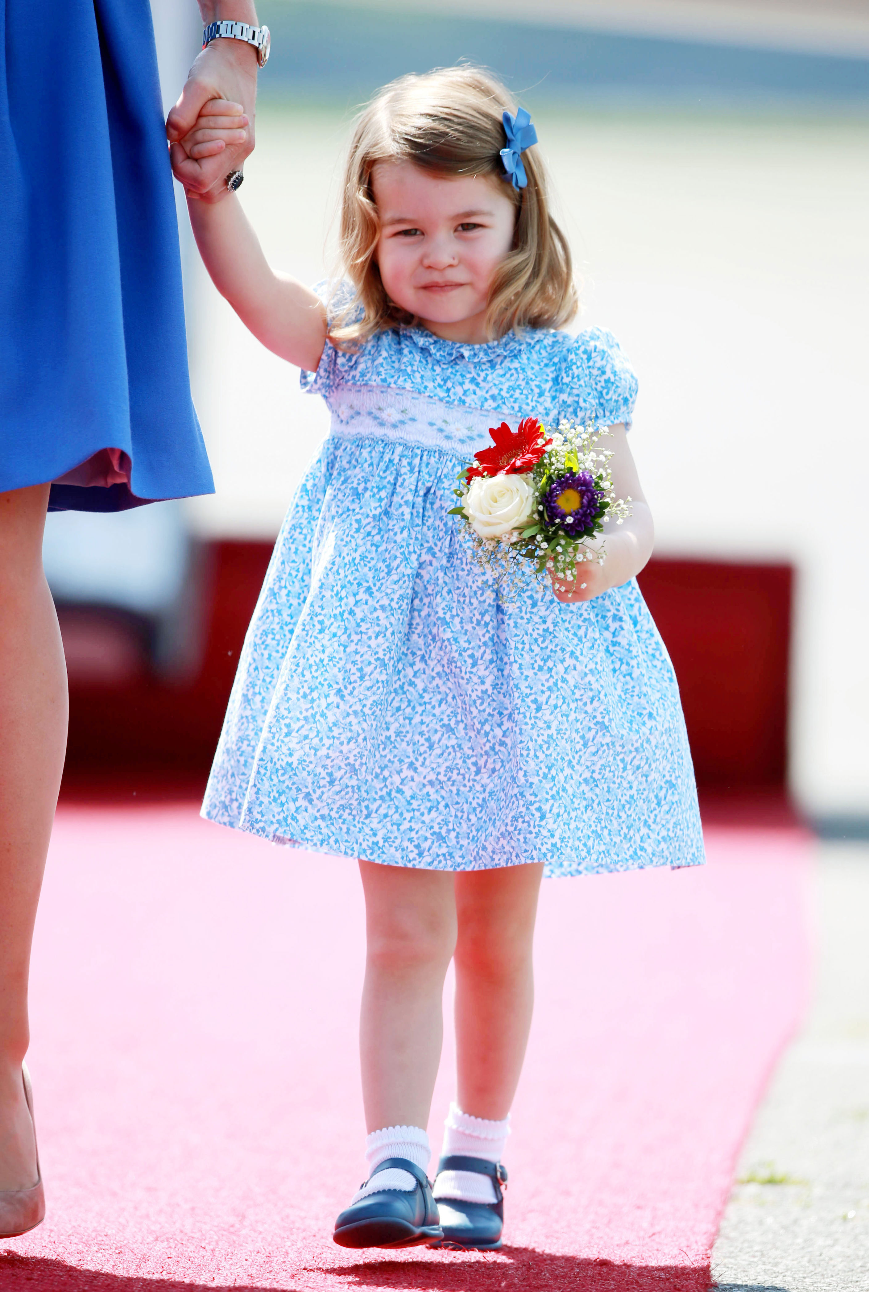 <p>Princess Charlotte clutched a bouquet of flowers as she arrived in Berlin with her parents on July 19, 2017.</p>