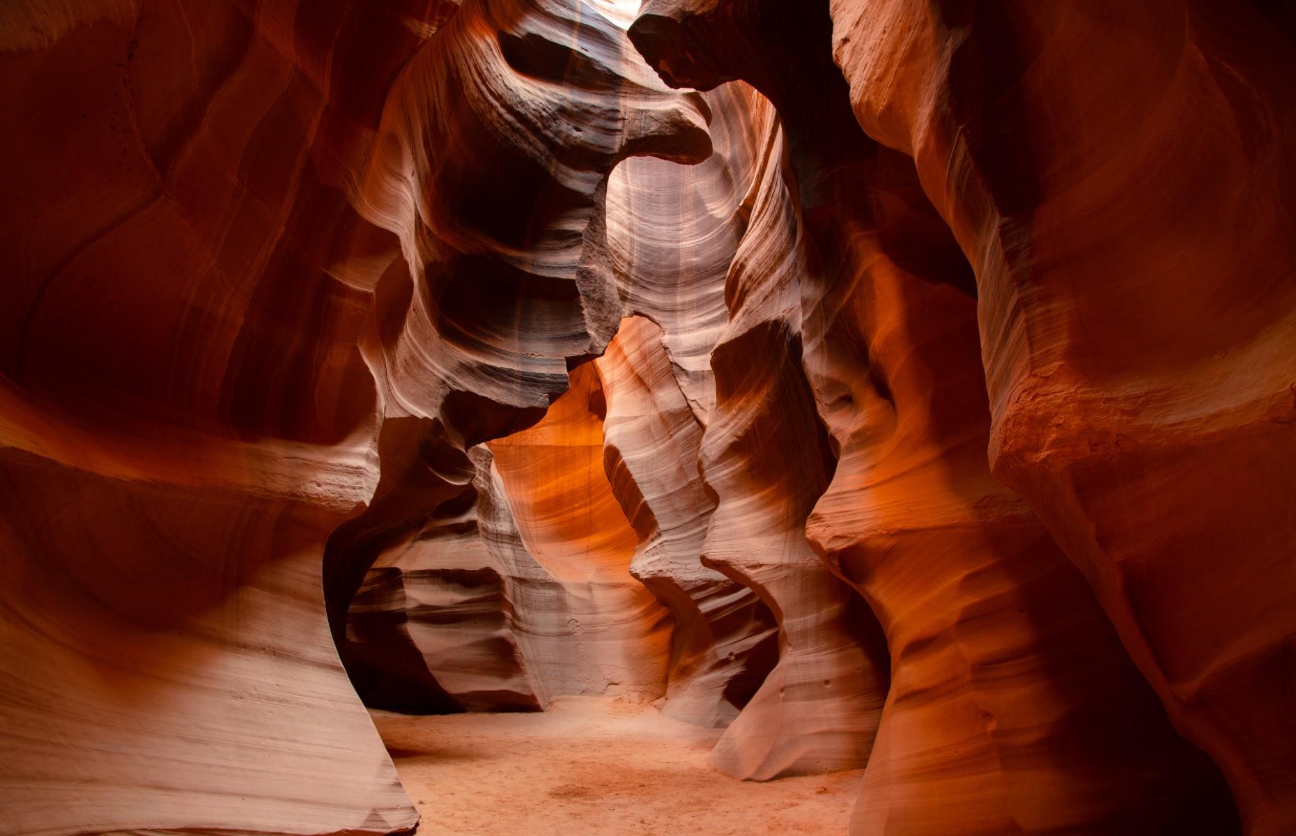 <p>From every angle, Antelope Canyon is totally mesmerizing, with its vivid crimson walls taking on myriad organic forms. The slot canyon, located on land belonging to the LeChee Chapter of the Navajo people, was formed over thousands of years by flash flooding carving into the sandstone. Forceful winds also hurled sand at its walls, creating the swirling shapes we see today. To experience it at its best, head down at midday to see the light pierce through the rock – you can book a tour to walk through it, although bear in mind the canyon is just eight to 12 feet (2.4–3.7m) wide in places. </p>