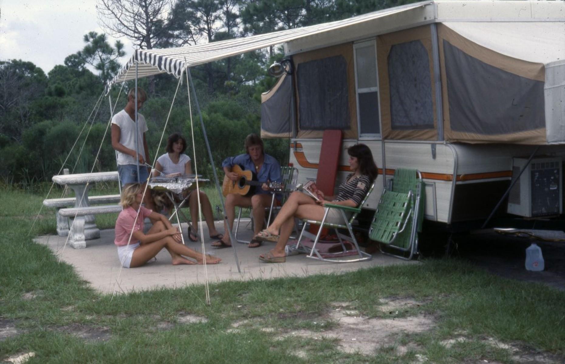 As motorhome and RV ownership grew, so did the need for more sites in which to park up. The successful management of public land, such as national parks and state parks, also helped to fuel camping’s popularity in this time. Seen here, a group of campers sit around by their trailer.