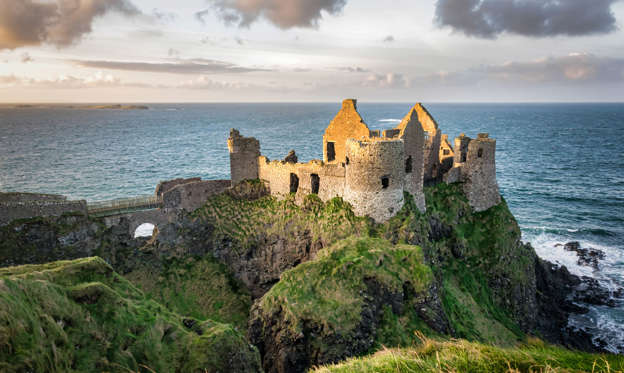 Diapositiva 2 de 8: This is a picture of the ruins of Dunluce Castle in Northern Ireland.  It was built in the 13th century on the top of a sea cliff looking out to the Atlantic Ocean
