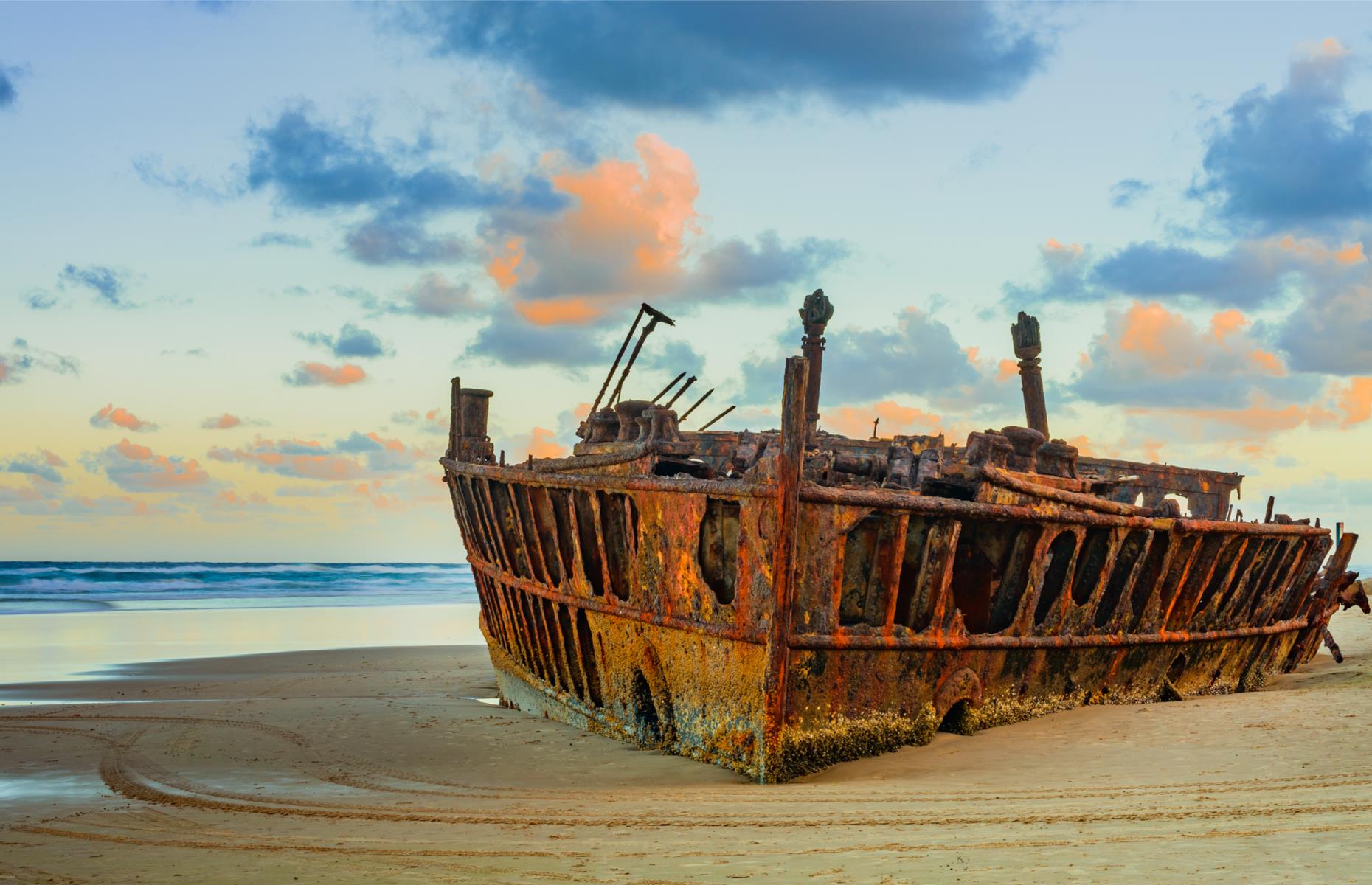 <p>The rusting remains of SS Maheno on Fraser Island’s vast 75 Mile Beach are an arresting sight and have become one its must-see landmarks. The rotting wreck was once an innovative ocean liner, built in 1905 and used to ferry passengers between Sydney and Auckland. She met her demise in 1935 on being towed to a Japanese wrecking yard, when a cyclone snapped the chain and she drifted onto the sand island’s shores. And here she’s stayed.</p>