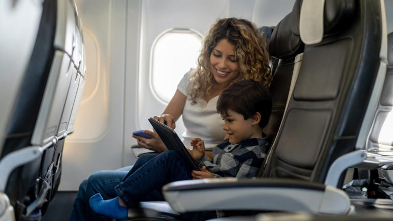 Loving mother and son playing with tablet during a flight looking very happy